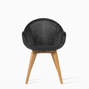 Vincent Sheppard Edgard dining chair in black with a rounded wicker seat and teak wooden legs.