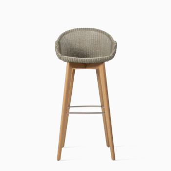 Vincent Sheppard Avril bar stool with a pebble-coloured woven seat and an oak base featuring a metal footrest.