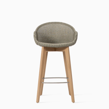 Vincent Sheppard Avril counter stool with a woven seat in a natural tone and an oak base featuring a metal footrest.