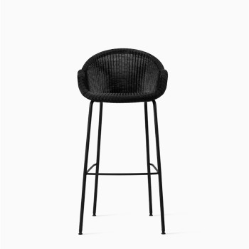 Vincent Sheppard black bar stool with a woven seat and curved backrest on slim metal legs.