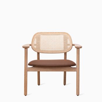 Vincent Sheppard Titus lounge chair with a natural wood frame, woven rattan backrest, and brown cushion.