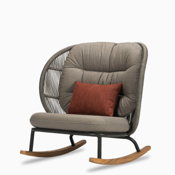 Vincent Sheppard Kodo rocking chair with a fossil grey frame, teak rockers, and carbon beige cushions, featuring a decorative spicy red cushion.