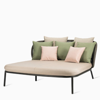 Vincent Sheppard Kodo daybed with a fossil grey frame, almond cushion, and decorative cushions in shades of green and blush.