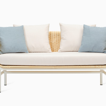 Vincent Sheppard Wicked three-seater lounge sofa in white and natural wicker, with cream cushions and decorative blue and cream pillows.