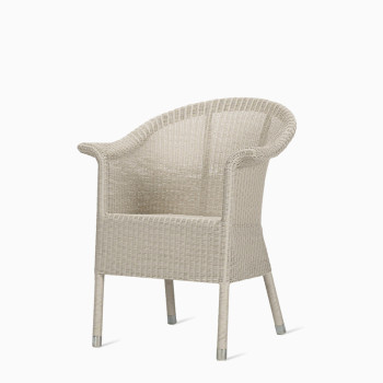 Vincent Sheppard Kenzo dining chair in old lace wicker, featuring a rounded back and armrests with metal-capped legs.