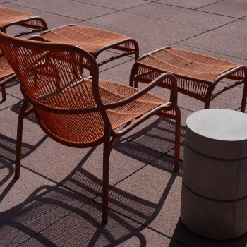 Close-up van een terracotta kleurige Loop loungestoel en voetensteun van Vincent Sheppard op het terras bij het zwembad van het Mix Brussel hotel.