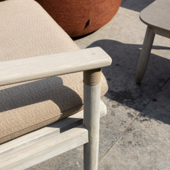 Close-up van een David lounge stoel met beige kussens, met nadruk op de houten armleuning en stofstructuur.