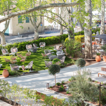 Espace de détente en plein air à La Bastide Bourelly avec des cocons Kodo, des sièges modulaires Kodo, des fauteuils à bascule Kodo et des chaises longues Roy sous de grands arbres.