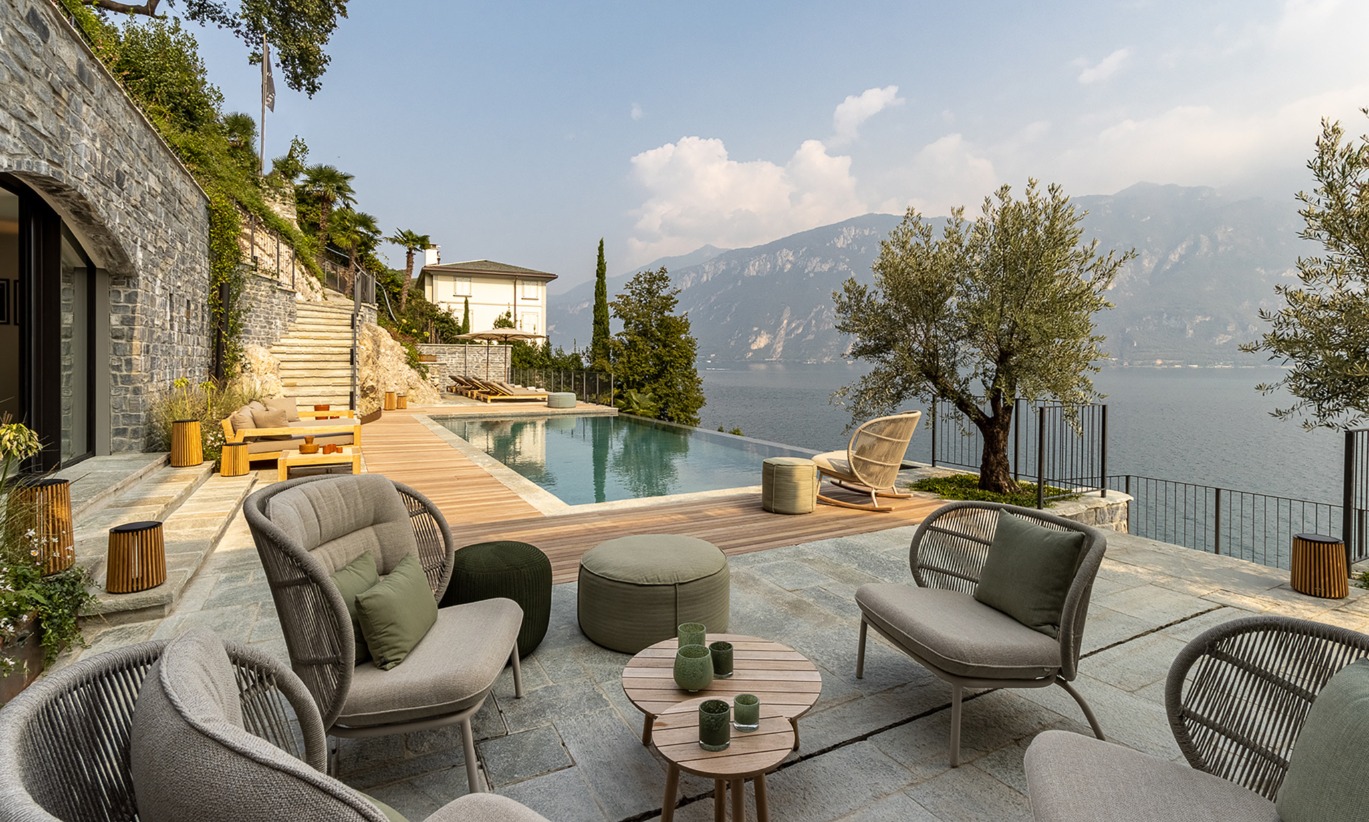 Terrasse extérieure au Breakwater Bellagio avec vue sur le lac, comprenant des fauteuils Kodo, Kodo Cocoon, chaise berçante Kodo, lampes Maya, table basse Anton, et tables d'appoint Anton.