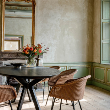 Elegant dining area featuring Vincent Sheppard Avril dining chairs with a steel base paired with an Albert dining table. The room has a classic decor with a large ornate mirror and a vase of flowers on the table.