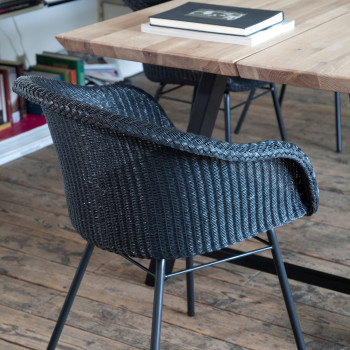 Close-up of Vincent Sheppard Avril dining chair with a steel base, featuring a woven design in a modern dining area with wooden floors.