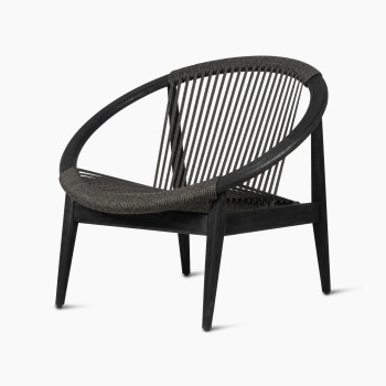 Fauteuil lounge Frida de Vincent Sheppard en Onyx Black, présenté sous un angle de 45 degrés, mettant en valeur le cadre en bois foncé et le dossier tressé.