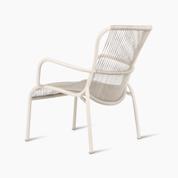 Schuin achteraanzicht van de Loop Lounge Chair van Vincent Sheppard in dune white, met geweven rugleuning en gebogen frame.