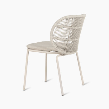 Vincent Sheppard Kodo dining chair with a dune white frame and an almond seat cushion, shown at a 135-degree angle from the back.