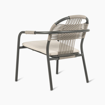 Rear angled view of the Vincent Sheppard Cleo lounge chair in fossil grey with an almond-coloured seat cushion and woven backrest