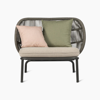 Kodo lounge chair by Vincent Sheppard in fossil grey with almond seat and blush and olive green decorative cushions, front view.