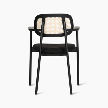 Back view of the Titus dining armchair by Vincent Sheppard, featuring a woven rattan backrest and black upholstered seat.