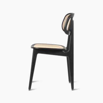 Side view of a Titus dining chair in black stained oak with a woven cane backrest and seat.