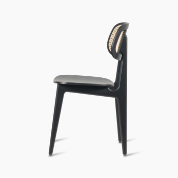 Side view of a Titus dining chair in black stained oak with a woven cane backrest and a solid black plywood seat.