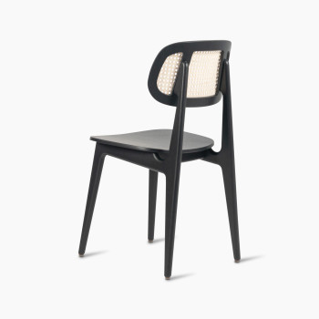 135-degree view of a Titus dining chair in black stained oak with a woven cane backrest and a solid black plywood seat.