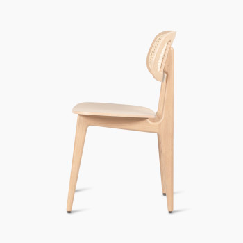 Side view of a Titus dining chair in natural varnished oak with a woven cane backrest and a solid plywood seat.