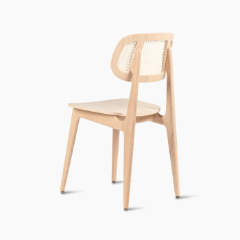 135-degree view of a Titus dining chair in natural varnished oak with a woven cane backrest and a solid plywood seat.