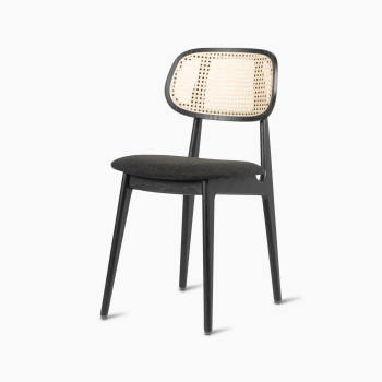 Titus dining chair in black stained oak with a rattan backrest and upholstered seat, angled side view.