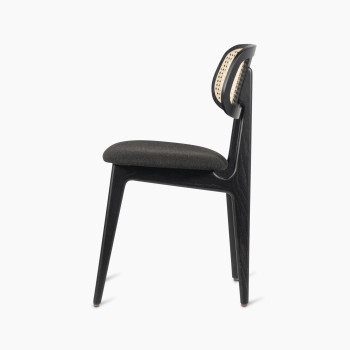 Titus dining chair in black stained oak with a rattan backrest and upholstered seat, side profile view.