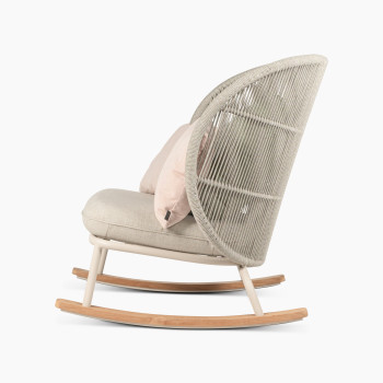 Vue latérale du fauteuil à bascule Kodo en blanc Dune avec siège amande et coussins décoratifs en blush et vert olive par Vincent Sheppard.