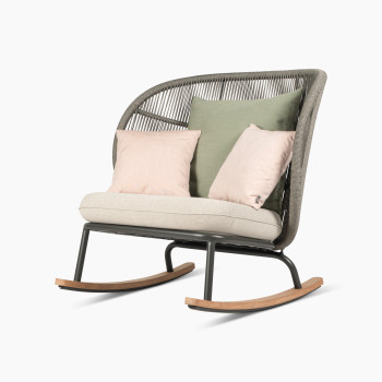 45-degree view of the Kodo rocking chair in fossil grey with almond seat and decorative cushions in olive green and blush by Vincent Sheppard.