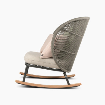 Vue latérale du fauteuil à bascule Kodo en gris fossile avec siège amande et coussins décoratifs en blush et vert olive par Vincent Sheppard.