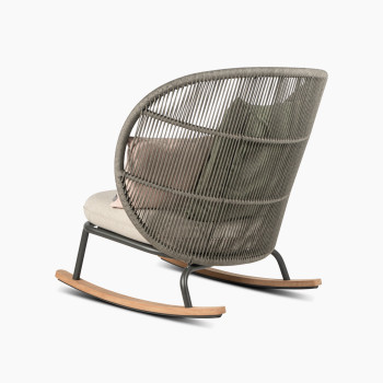 Rear 135-degree view of the Kodo rocking chair in fossil grey with almond seat and decorative cushions in blush and olive green by Vincent Sheppard.