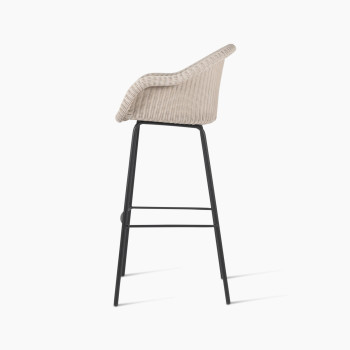 Side view of the Edgard barstool by Vincent Sheppard, featuring an old lace-coloured wicker seat and a black steel base.