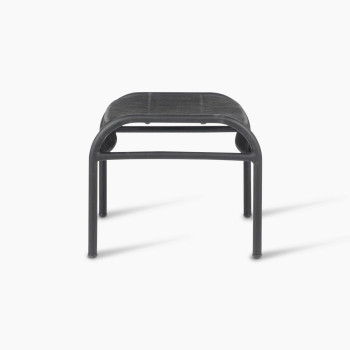 Side view of the Loop footrest in black by Vincent Sheppard, featuring a curved metal frame and a woven Lloyd Loom surface designed for resting feet.