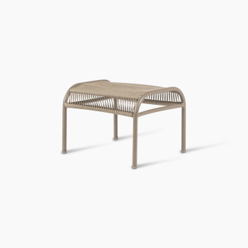 Side view of the Loop footrest in taupe by Vincent Sheppard, featuring a curved metal frame and a tightly woven Lloyd Loom surface designed for resting feet.