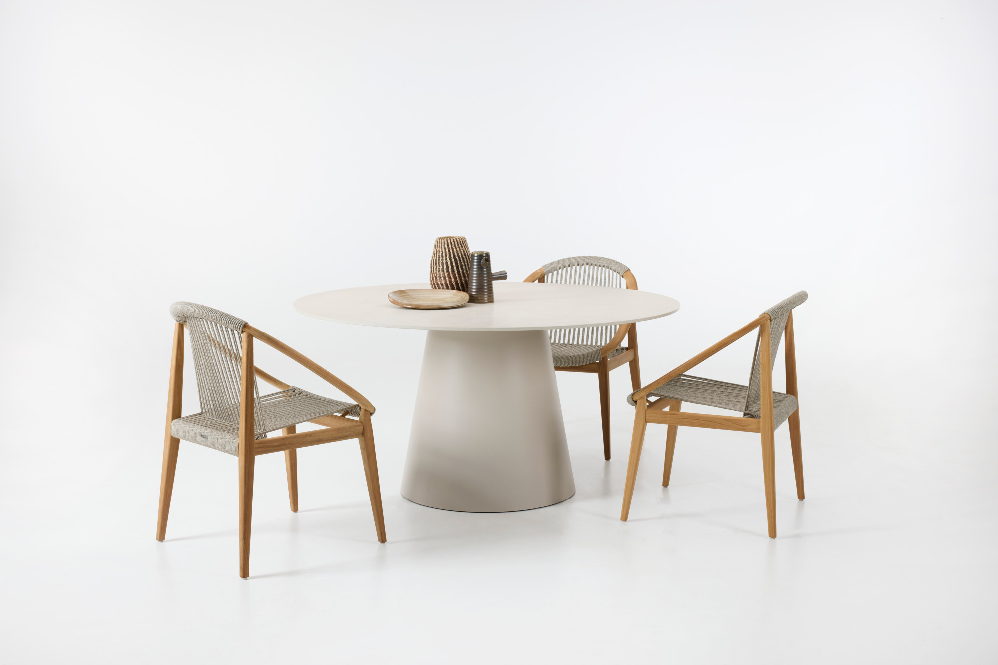 Sandro dining table with a cone-shaped base and Frida dining chairs featuring rope seats and wooden frames, set against a plain white background.