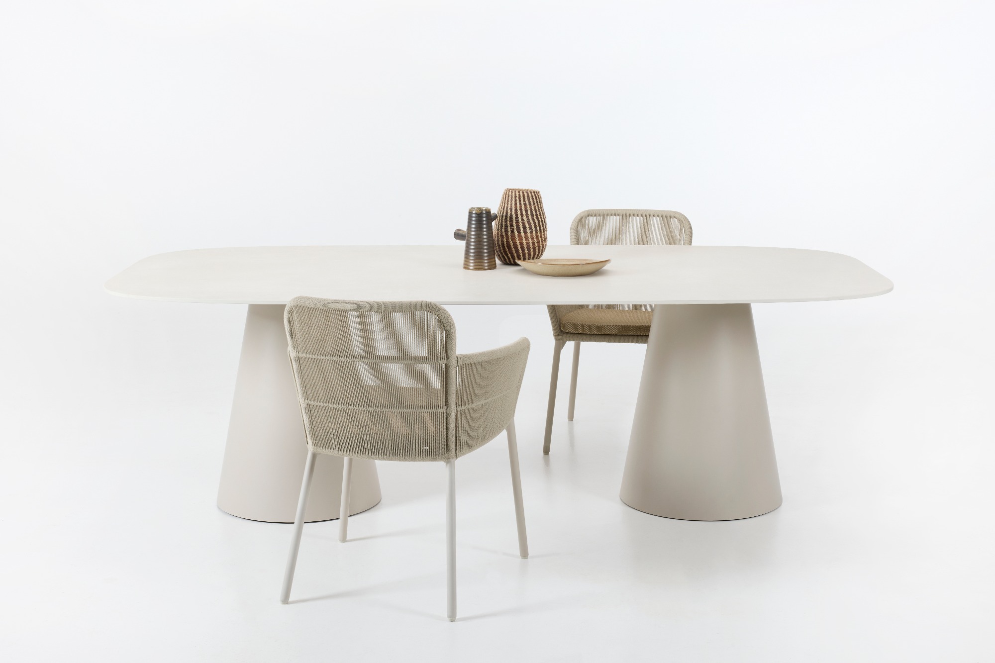 Sandro dining table in Dune White with a ceramic Portland top, paired with Akari dining chairs featuring rope detailing and white metal frames, set against a plain white background.