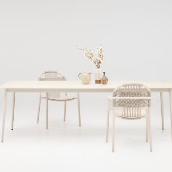 Vincent Sheppard Cleo dining armchairs in dune white paired with the Max dining table in dune white with a ceramic Portland top, styled with decorative vases and branches.